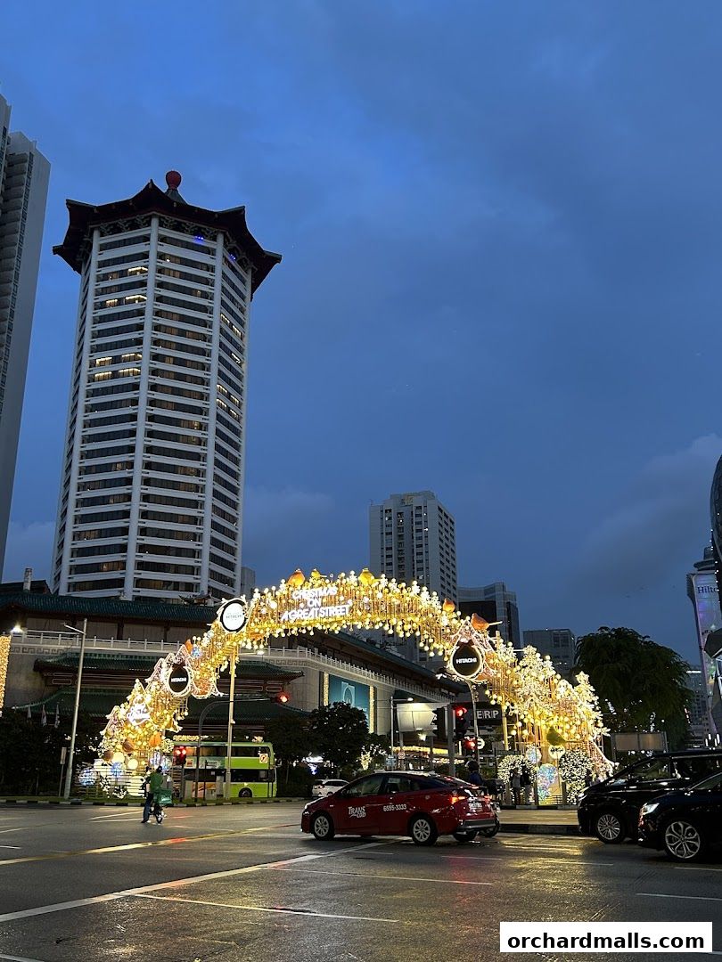A street scene at dusk with festive Christmas lights adorning an archway.