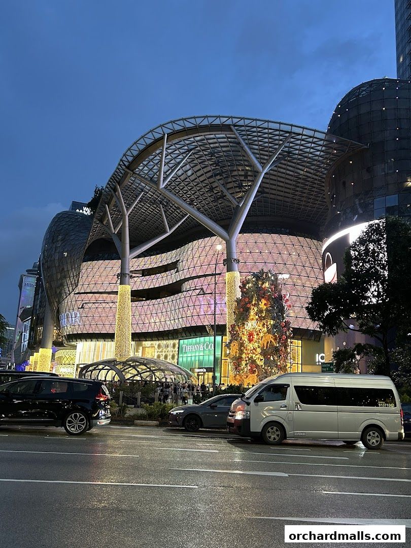 The ION Orchard building at dusk, featuring a distinctive tree-like canopy and illuminated facade.