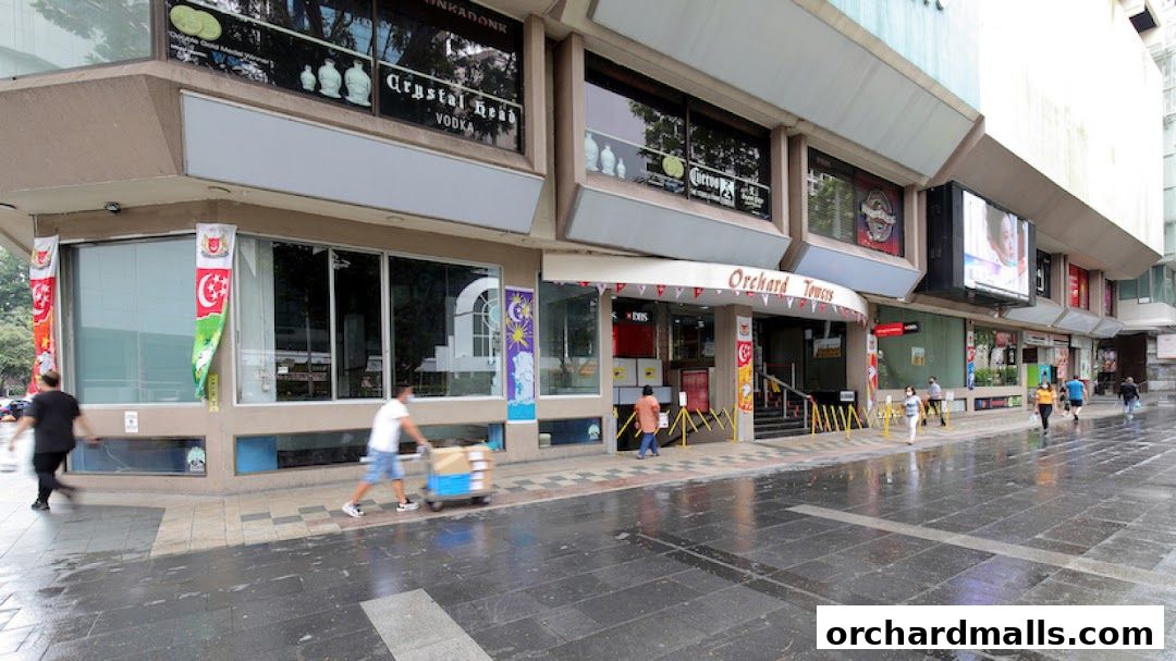 Exterior view of Orchard Towers with various shops and people walking by.