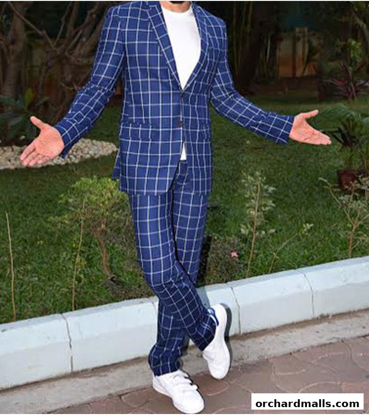 A person wearing a blue checkered suit and white sneakers stands with arms outstretched.
