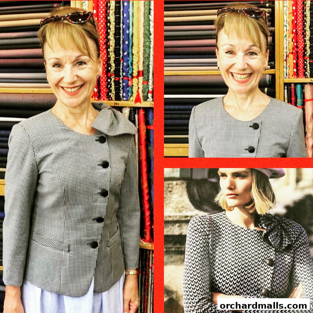A woman smiles in front of shelves filled with colorful fabrics at a tailor shop.