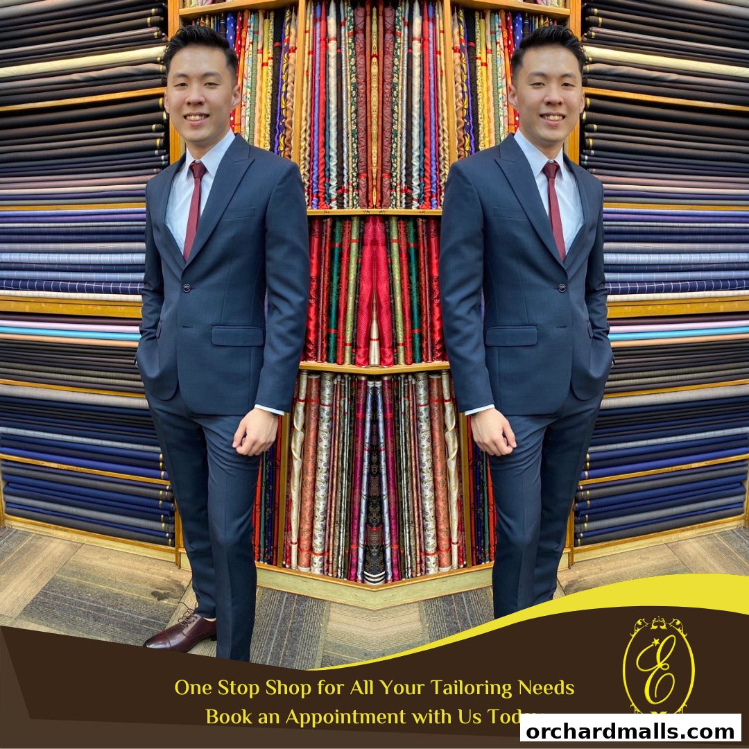 A man in a suit stands in front of shelves filled with colorful fabrics at Ehkay Corner Tailors.
