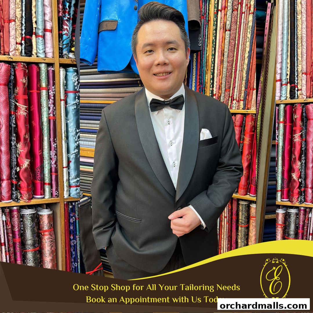 A man in a tuxedo stands in front of shelves filled with colorful fabrics at a tailor shop.