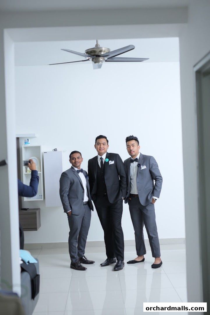 Three men in tailored suits posing for a photo, with a photographer visible on the left.