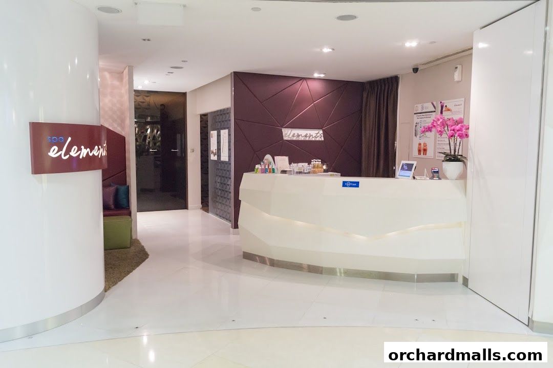 The reception area of a modern spa with a white counter, orchids, and product displays.