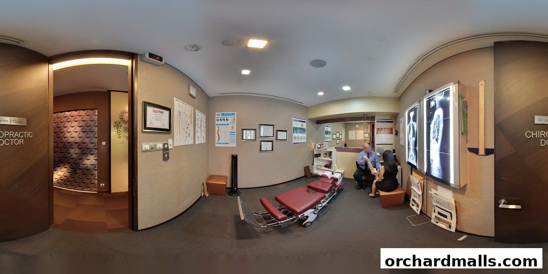 Interior of a chiropractic clinic with a treatment table, X-rays, and staff attending to a patient.
