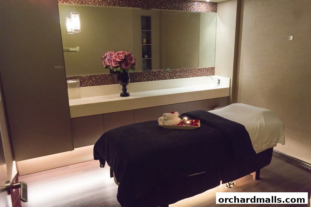 A treatment room with a massage bed, towels, candles, and a vase of flowers.