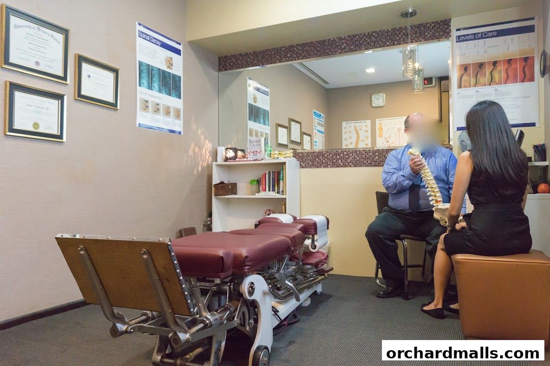 A chiropractor consults with a patient, using a spine model to explain treatment.