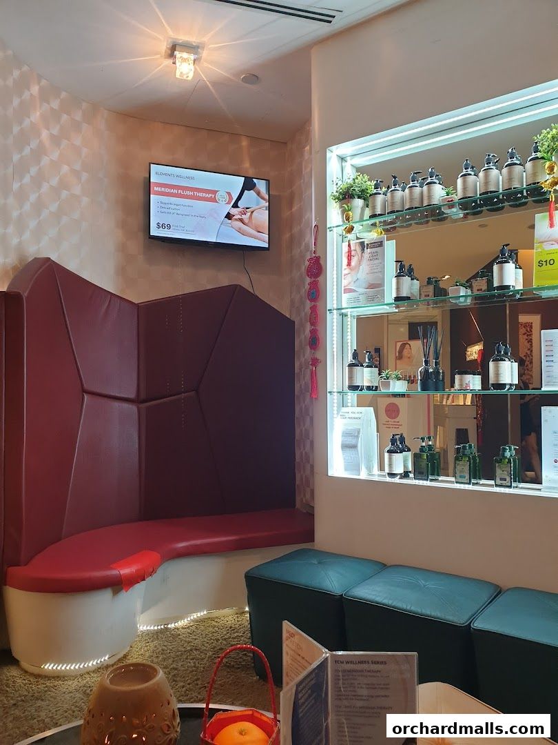 Interior of a wellness spa with a TV screen, seating, and shelves displaying products.