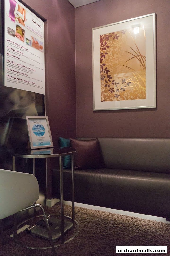 A waiting area with a sofa, table, and a list of popular slimming treatments.