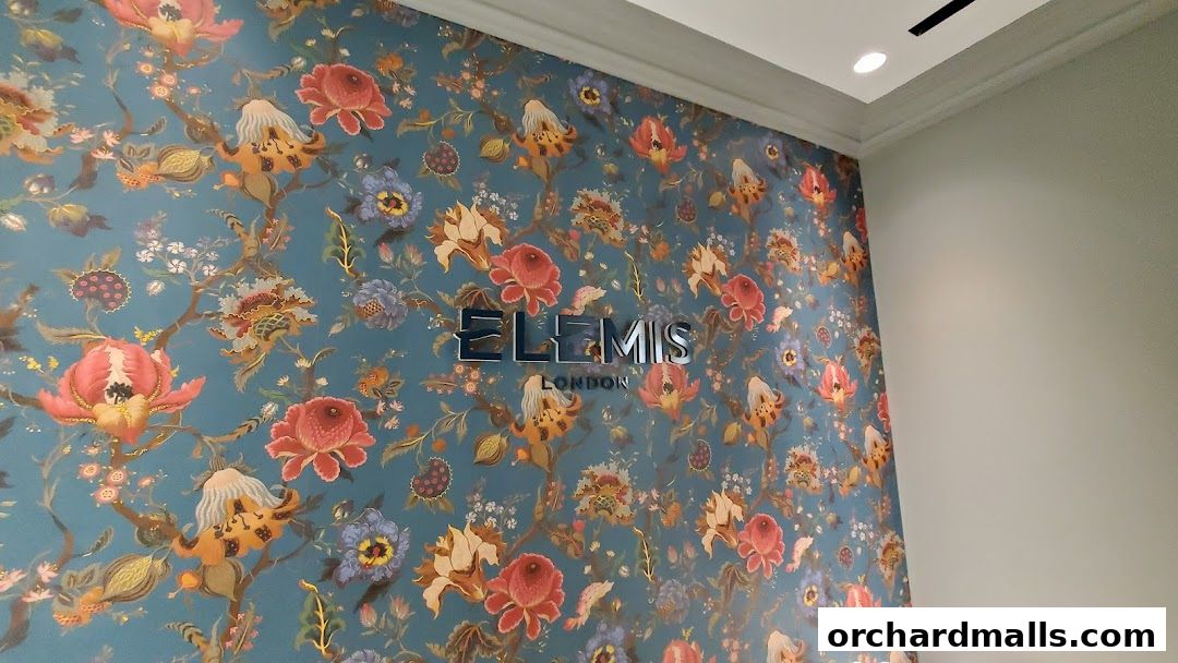 The Elemis London logo is displayed on a wall with a vibrant floral wallpaper.