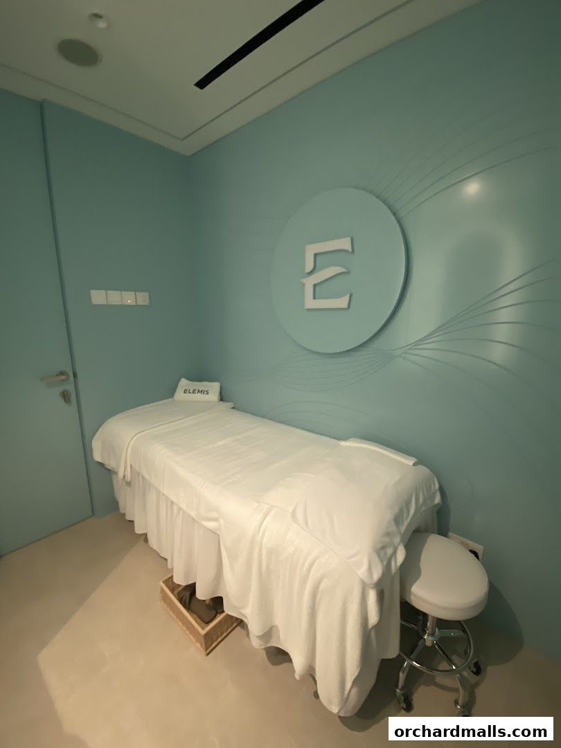 A treatment room at Elemis London with a massage bed and a stool.