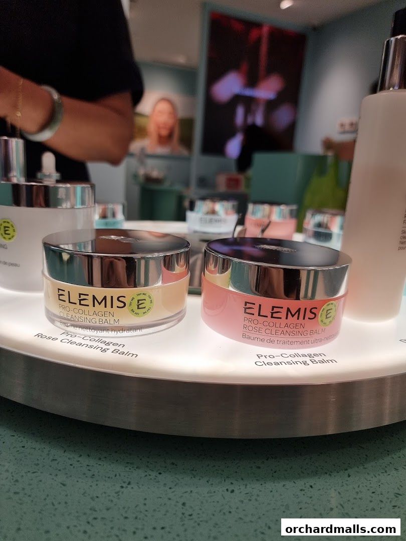 Elemis Pro-Collagen Cleansing Balms displayed on a lit circular stand.