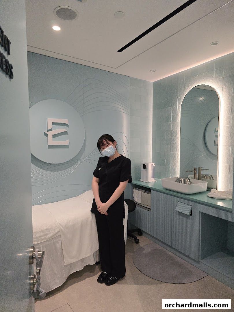 A spa treatment room with a massage bed, a therapist, and a vanity area.