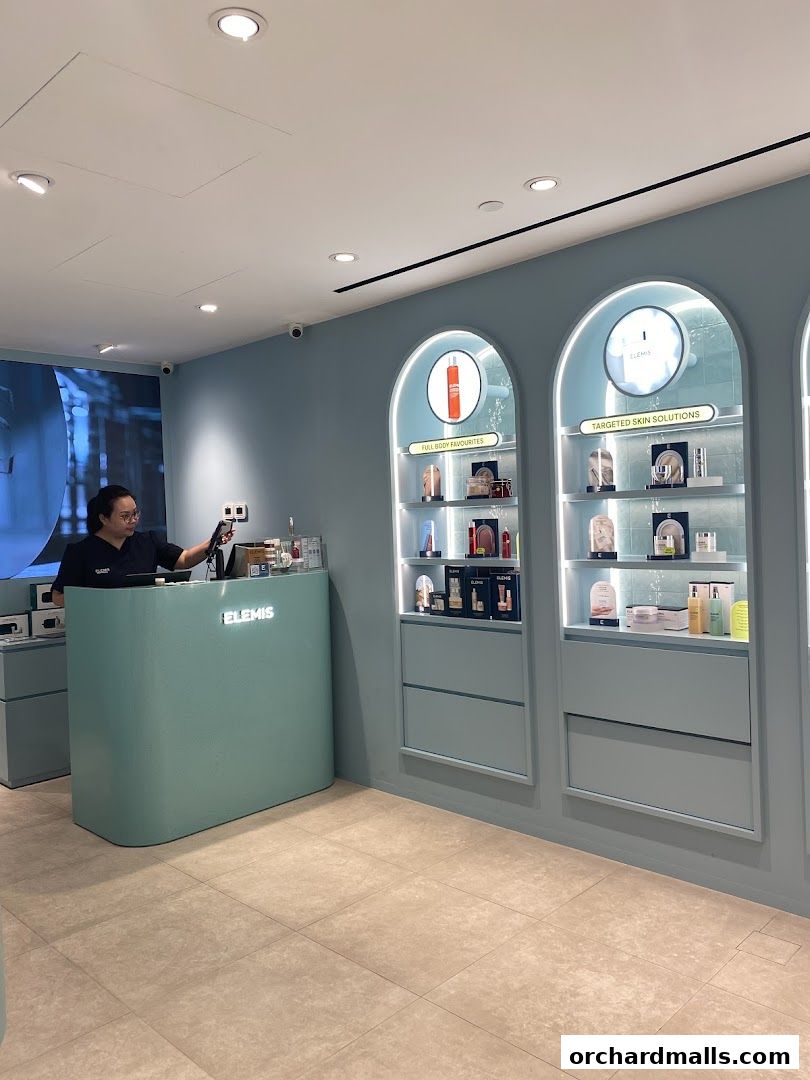 Interior of an Elemis London shop with a reception desk and illuminated display shelves.