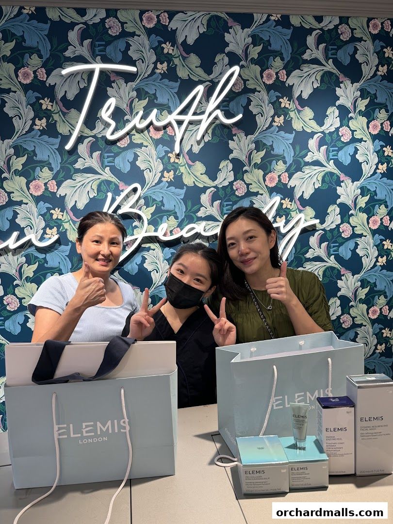Three smiling women pose with Elemis London shopping bags and skincare products.