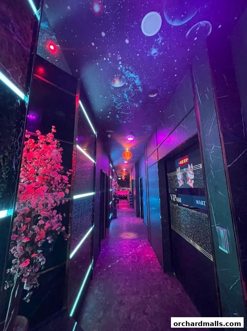 A dimly lit hallway with neon lights, galaxy-themed ceiling, and decorative cherry blossoms.