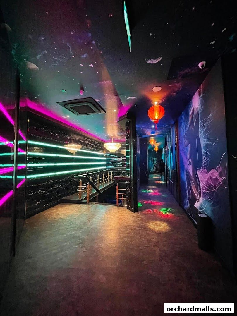 A dimly lit hallway with neon lights, galaxy-themed ceiling, and colorful floor projections.