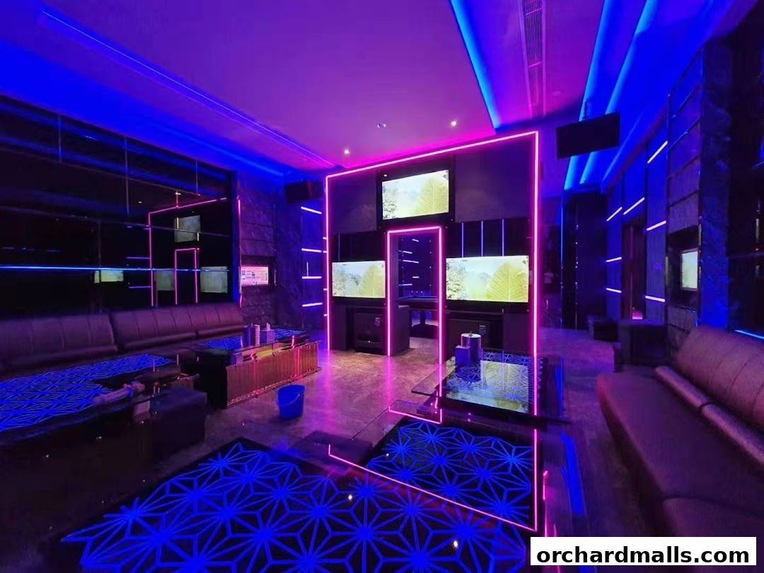 A modern KTV room with neon lights, comfortable seating, and large screens.