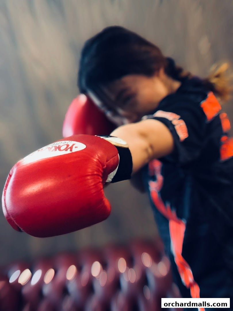 A person wearing red boxing gloves throws a punch in a gym.