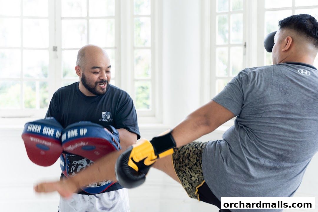 A trainer holds pads for a kickboxing student in a bright, airy studio.