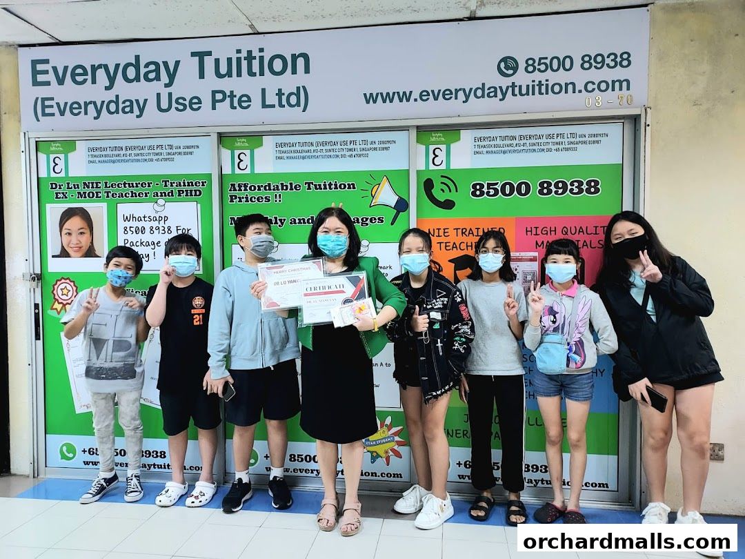 A group of students and a teacher pose in front of the Everyday Tuition shop.