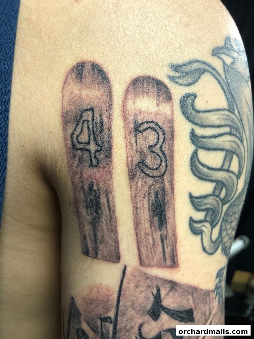 Close-up of a tattoo featuring wooden planks with numbers 4 and 3.