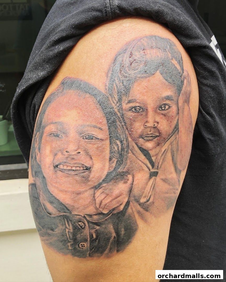 A detailed tattoo of two children's faces on a person's arm.