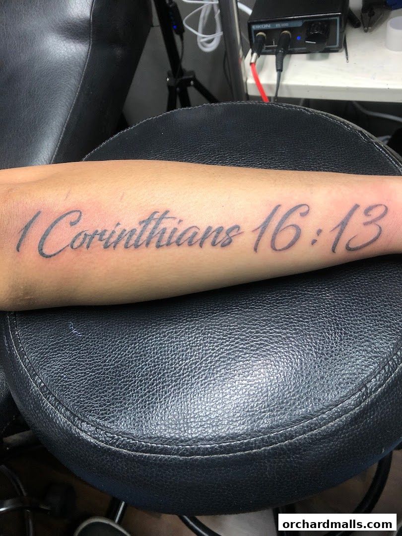 A close-up of a tattoo on an arm with the text '1 Corinthians 16:13'.