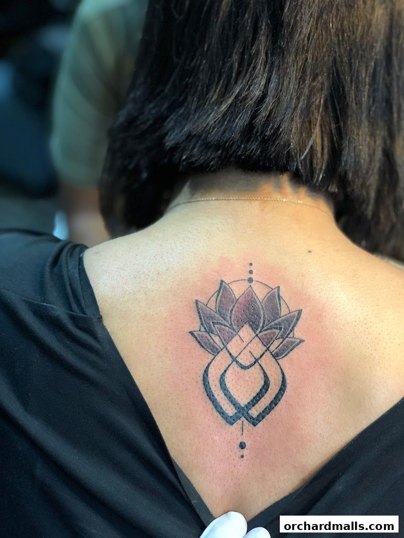 A person's back with a newly inked lotus flower tattoo.