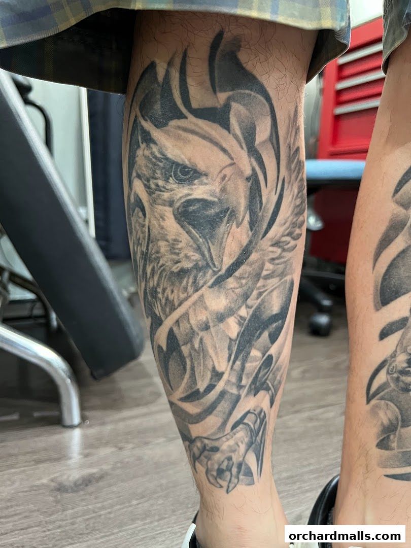 A detailed black and grey tattoo of an eagle on a person's leg.