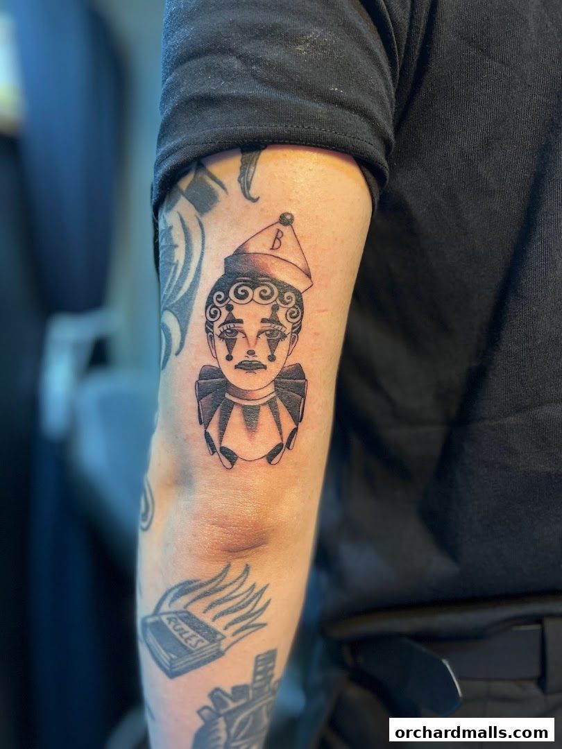 A close-up of a tattoo of a clown face on a person's arm.
