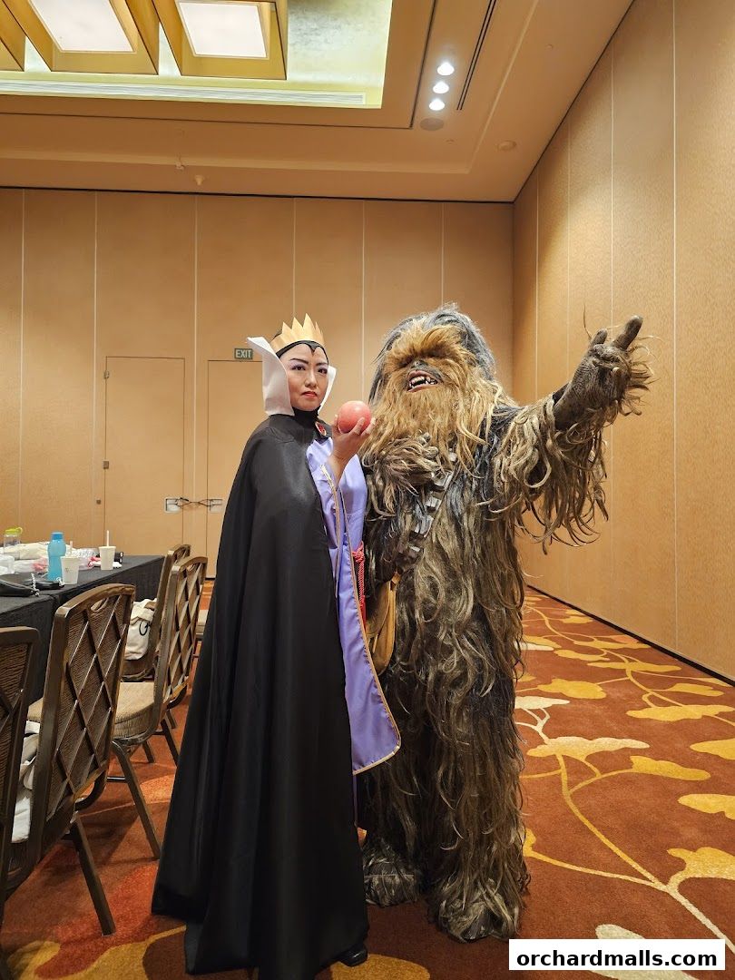 A person in a Snow White Evil Queen costume stands with a Chewbacca character.