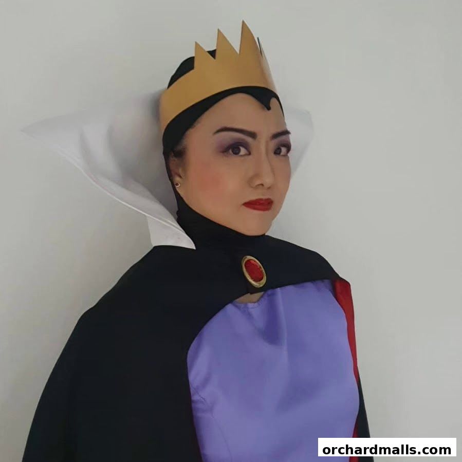 A woman in a queen costume with a crown and cape poses for a photo.