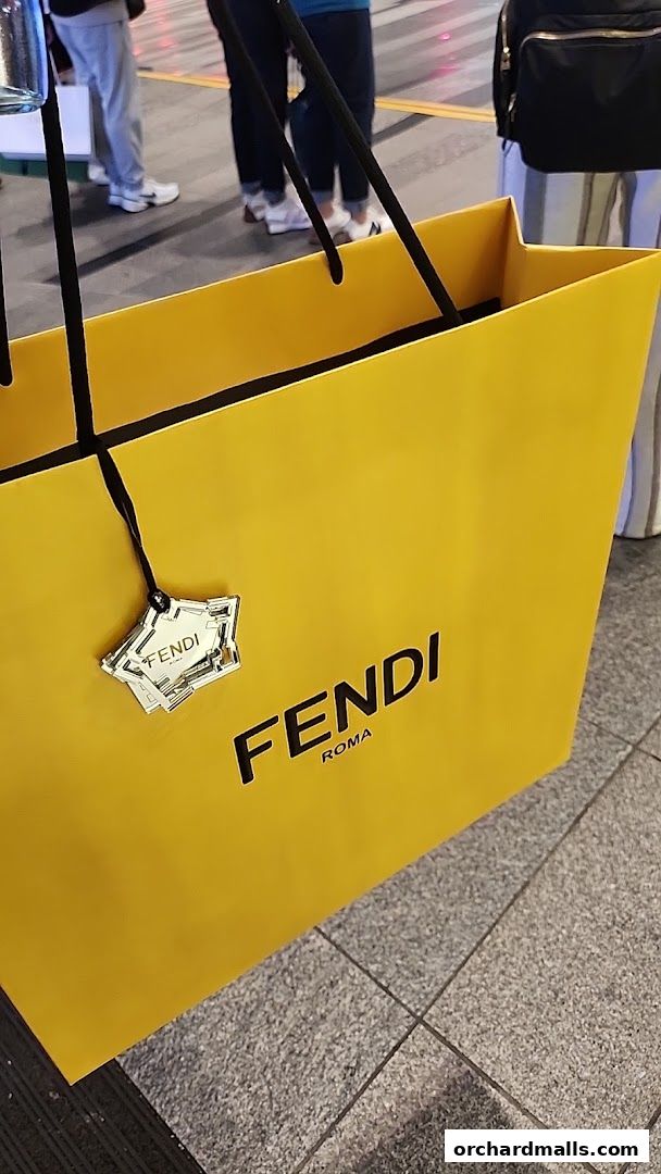 A bright yellow Fendi shopping bag with a star-shaped tag and the Fendi Roma logo.