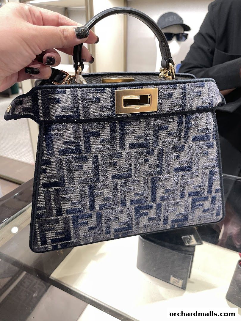A hand holds a Fendi bag with the iconic FF logo pattern.