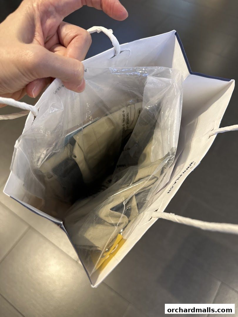 A hand holds a shopping bag containing FILA branded items in plastic packaging.