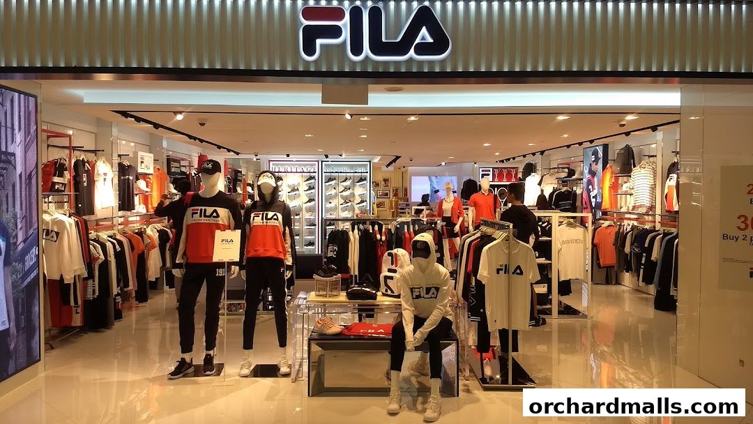 The entrance of a FILA store showcasing apparel on mannequins and racks, with shoes displayed on shelves.