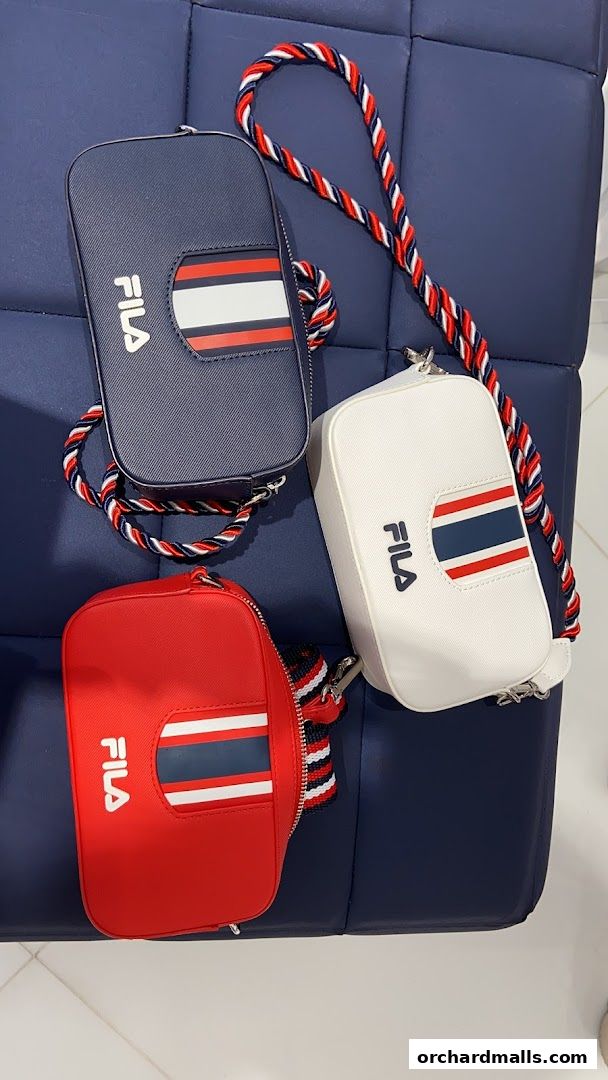 Three Fila crossbody bags in navy, white, and red with striped accents and braided straps.