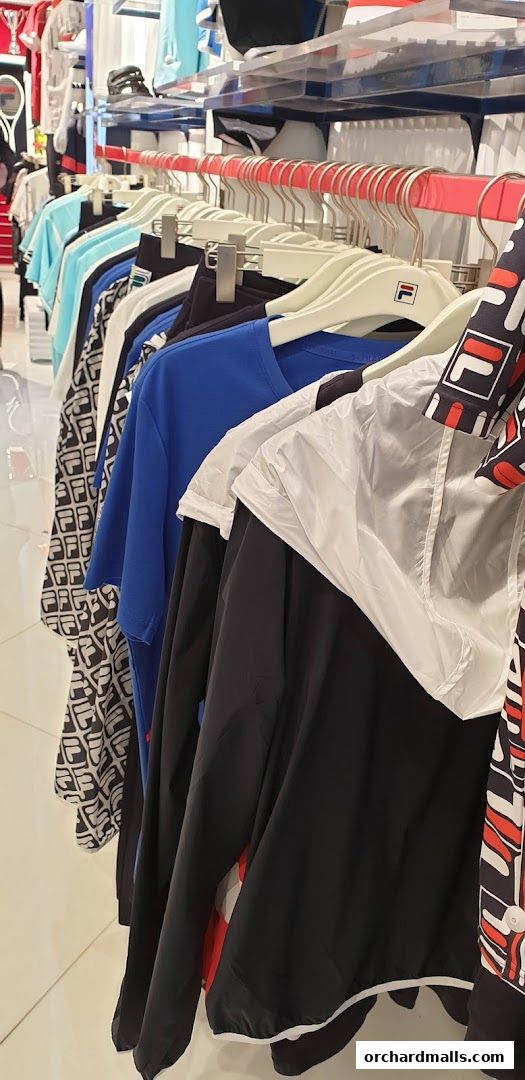 A rack of FILA branded apparel, including t-shirts and jackets, displayed in a retail store.