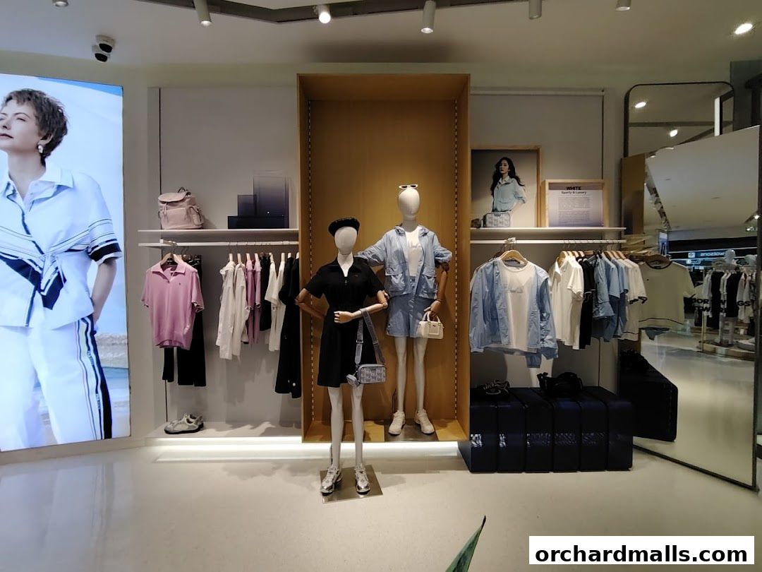 A Fila store display featuring mannequins and clothing on racks, with a large digital advertisement.