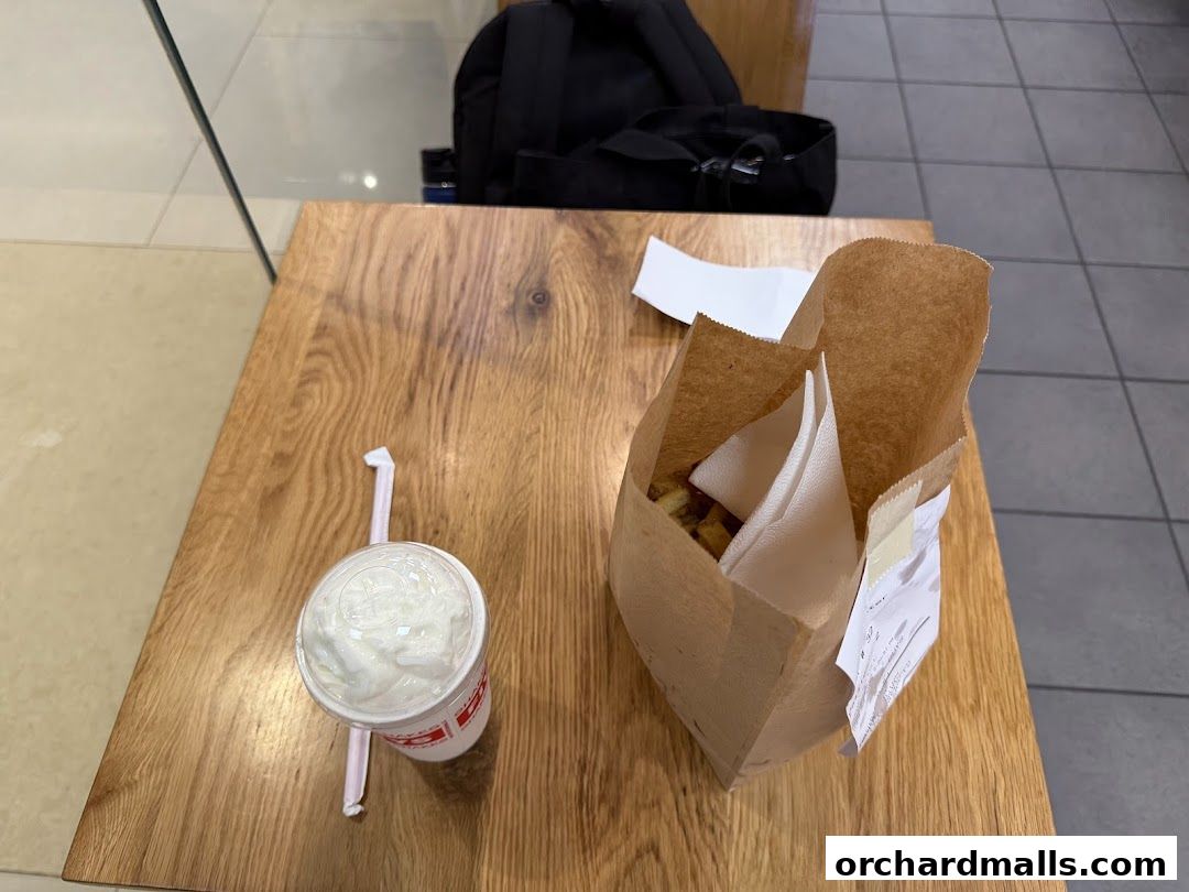 A paper bag of fries and a milkshake on a wooden table.