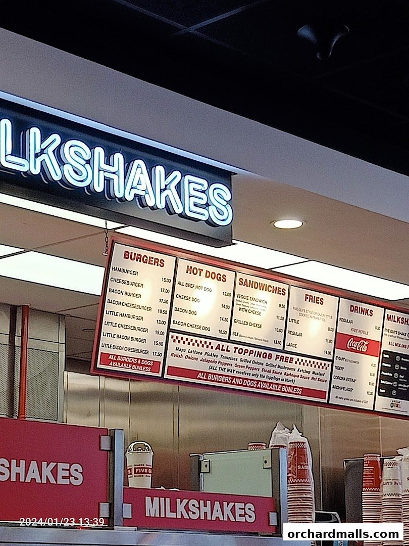 A menu board displaying burgers, hot dogs, sandwiches, fries, drinks, and milkshakes at Five Guys.
