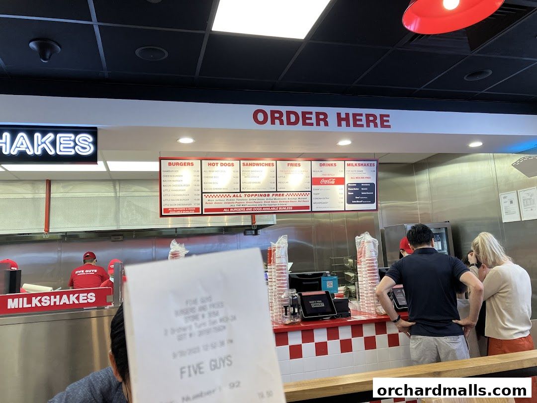 A Five Guys restaurant counter with an order here sign and a visible menu board.