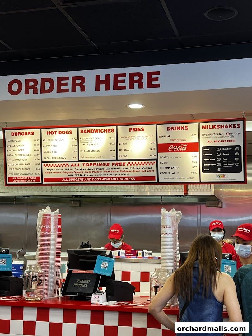 A Five Guys restaurant menu board displaying burgers, hot dogs, sandwiches, fries, drinks, and milkshakes.