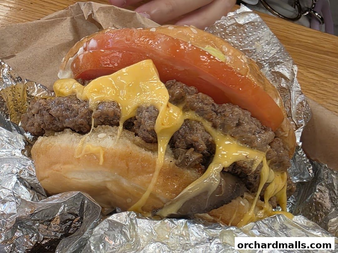 A close-up of a juicy Five Guys burger with melted cheese and fresh tomato.