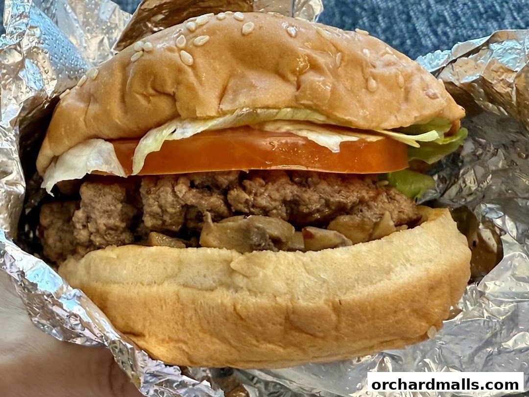 A close-up shot of a delicious Five Guys burger with fresh toppings and mushrooms.