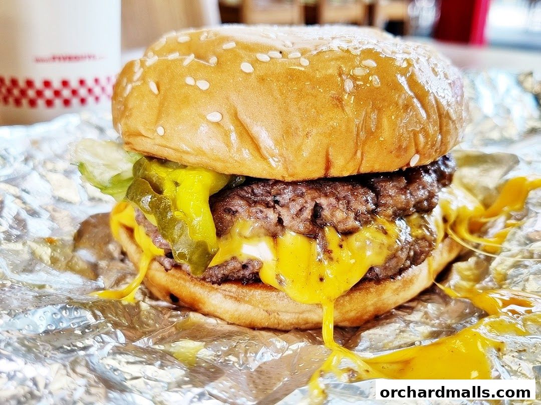 A close-up shot of a juicy Five Guys burger with melted cheese and pickles.
