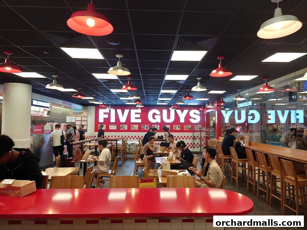 Interior view of a busy Five Guys restaurant with customers dining and ordering.