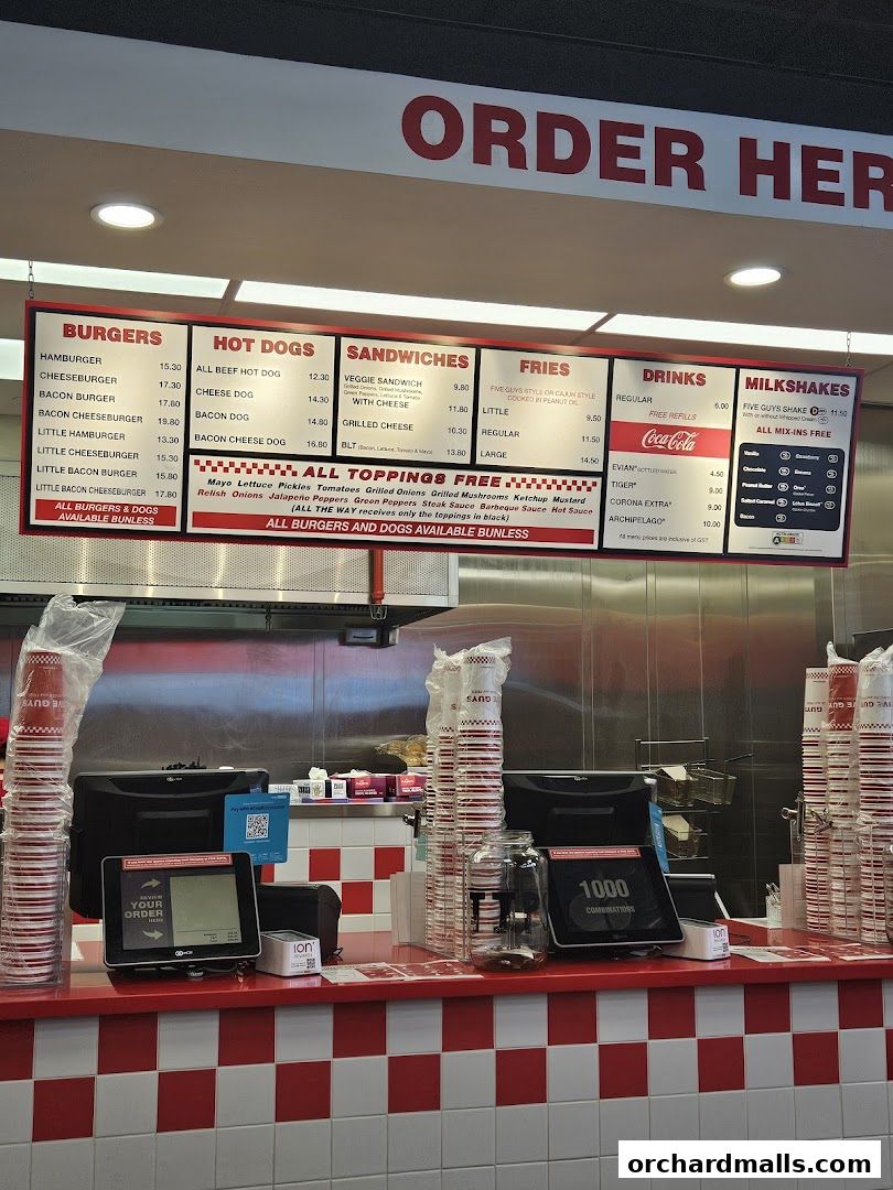 A Five Guys menu board displaying burgers, hot dogs, sandwiches, fries, drinks, and milkshakes.